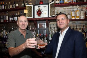 From left: Brad & Adrian toast the arrival of the exclusive rum (open box in background) that’s now on sale at their Sheffield bar at £250 a shot.